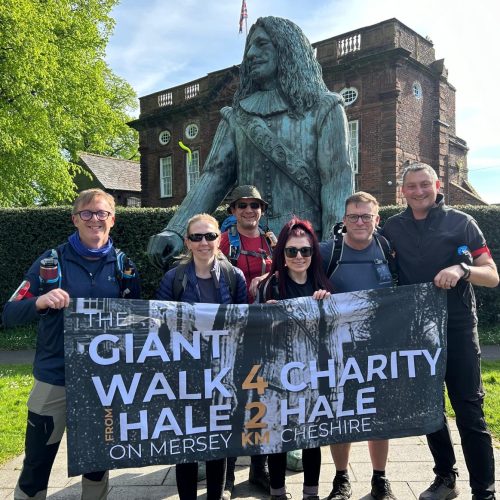 a group of people holding a sign by a tall statue